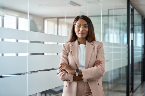 A woman in a suit standing in front of a glass wall.