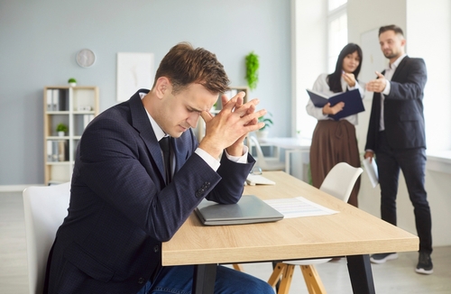 dejected manager leaning over closed laptop at office desk